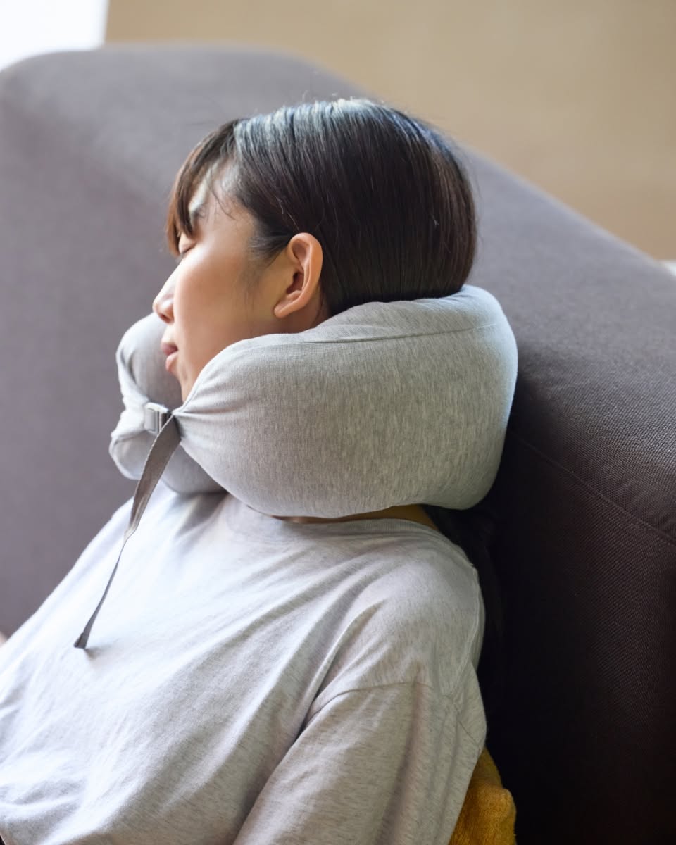 Gray inflatable travel neck pillow on a sofa