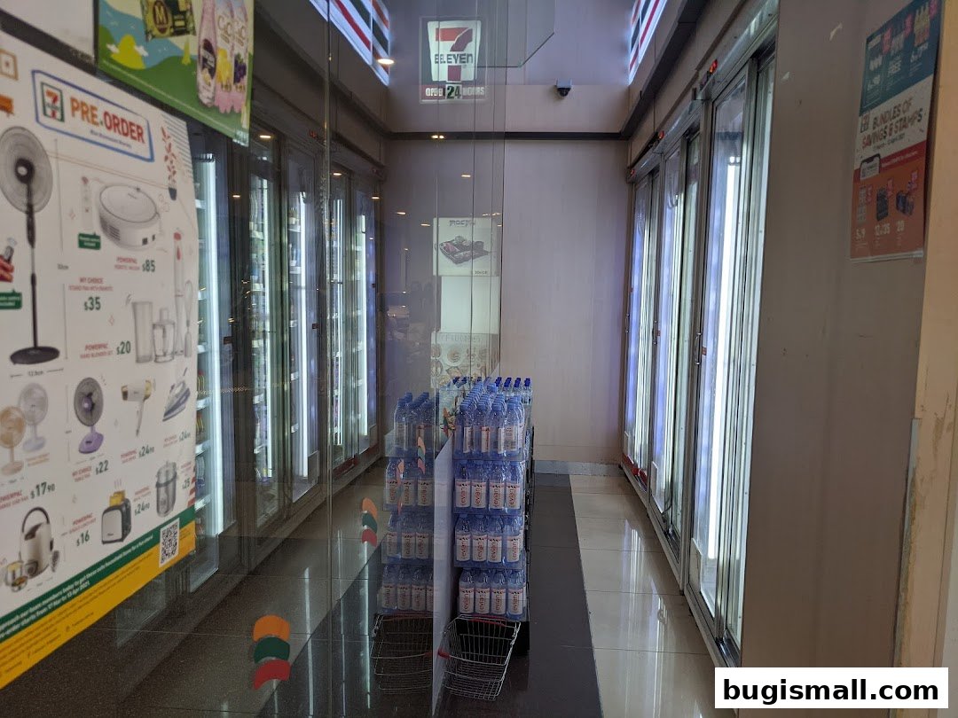 Interior view of a 7-Eleven store with refrigerated display cases and promotional posters.