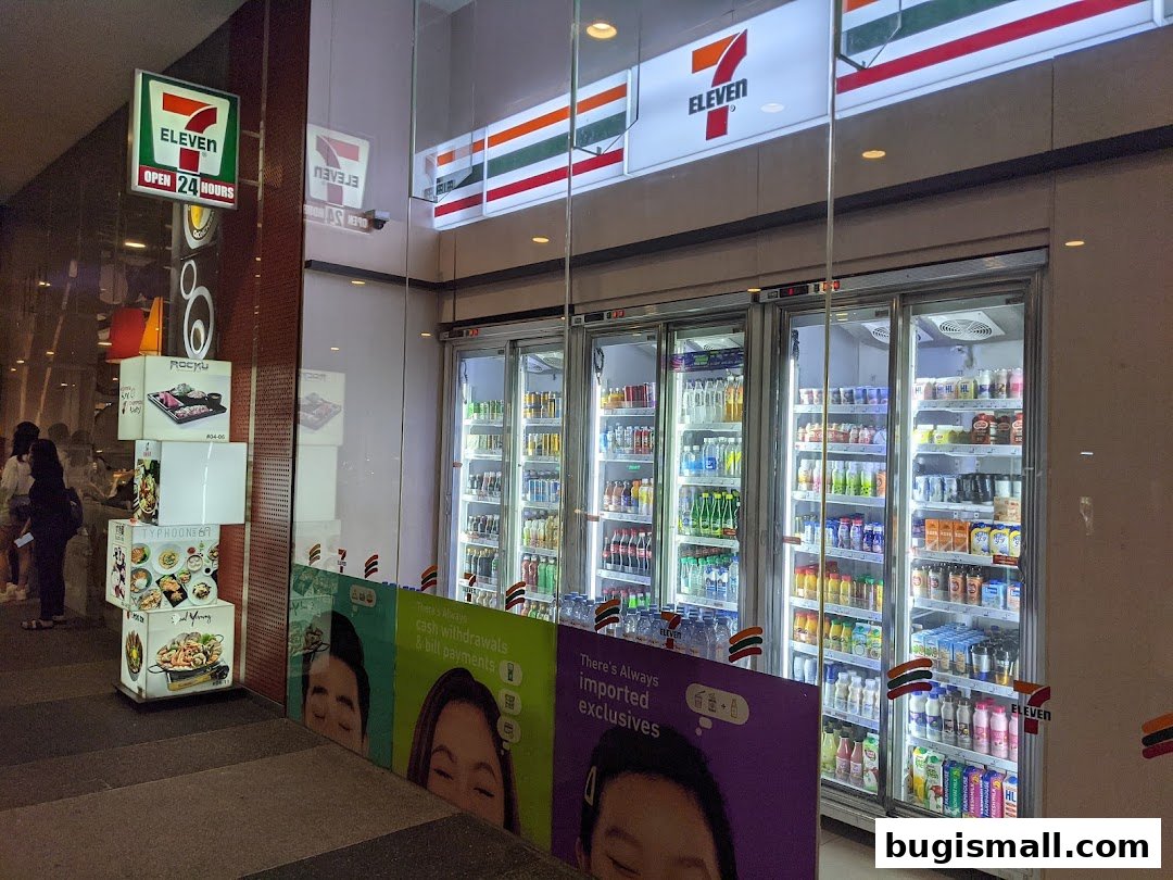 The exterior of a 7-Eleven convenience store with illuminated signage and refrigerated display cases.
