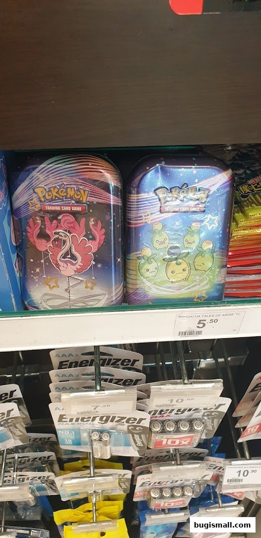 Pokemon trading card game tins and Energizer batteries displayed on shelves.