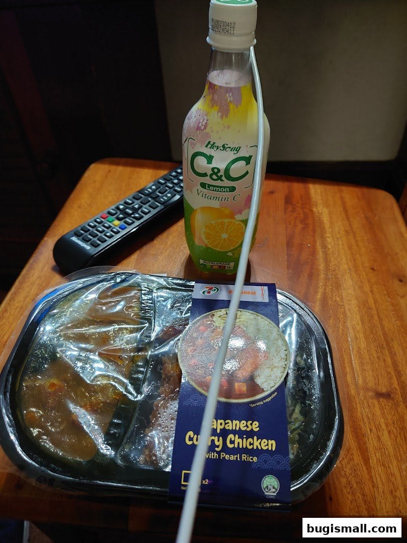 A meal from 7-Eleven featuring Japanese Curry Chicken with Pearl Rice and a bottle of C&C Lemon Vitamin C drink.