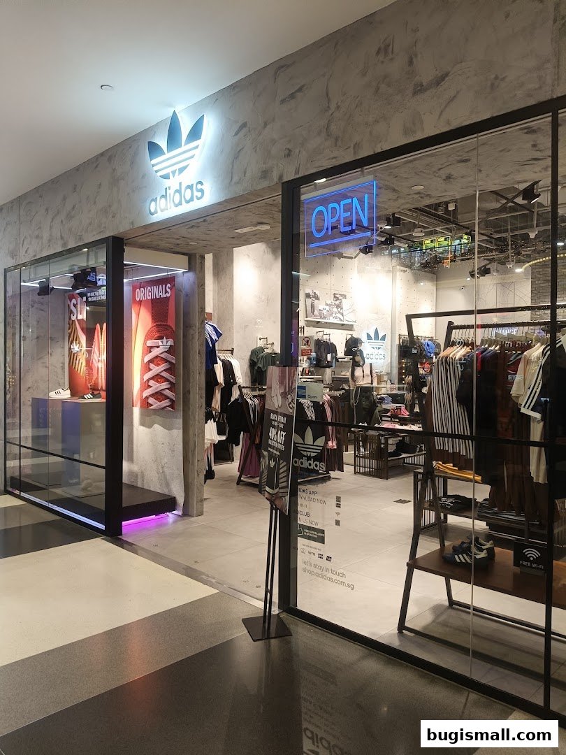 The entrance of an Adidas Originals store with clothing displays and an 'OPEN' sign.