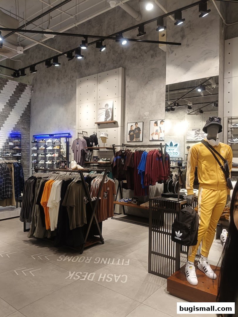 Interior of an Adidas Originals store with clothing racks, a mannequin, and signage.