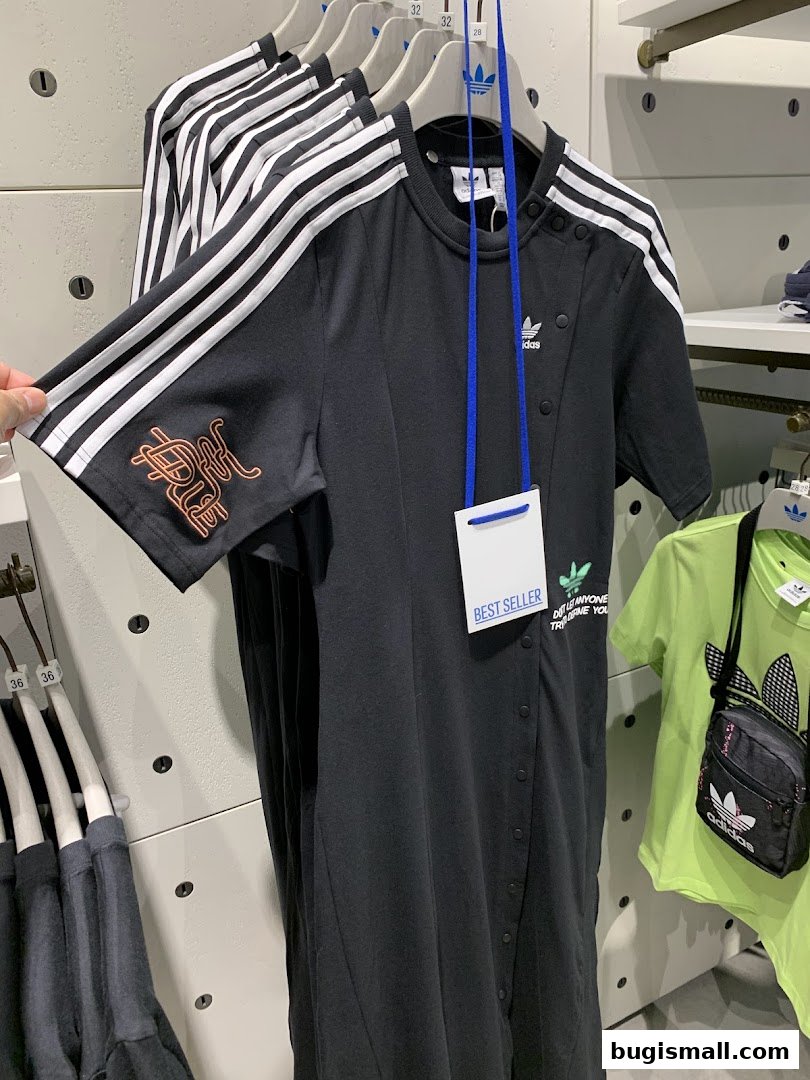 A black Adidas dress with white stripes on the sleeves is displayed in a store.
