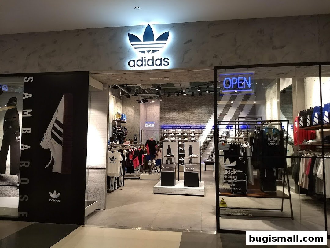 The entrance of an Adidas Originals store showcasing apparel and footwear, with an "OPEN" sign.