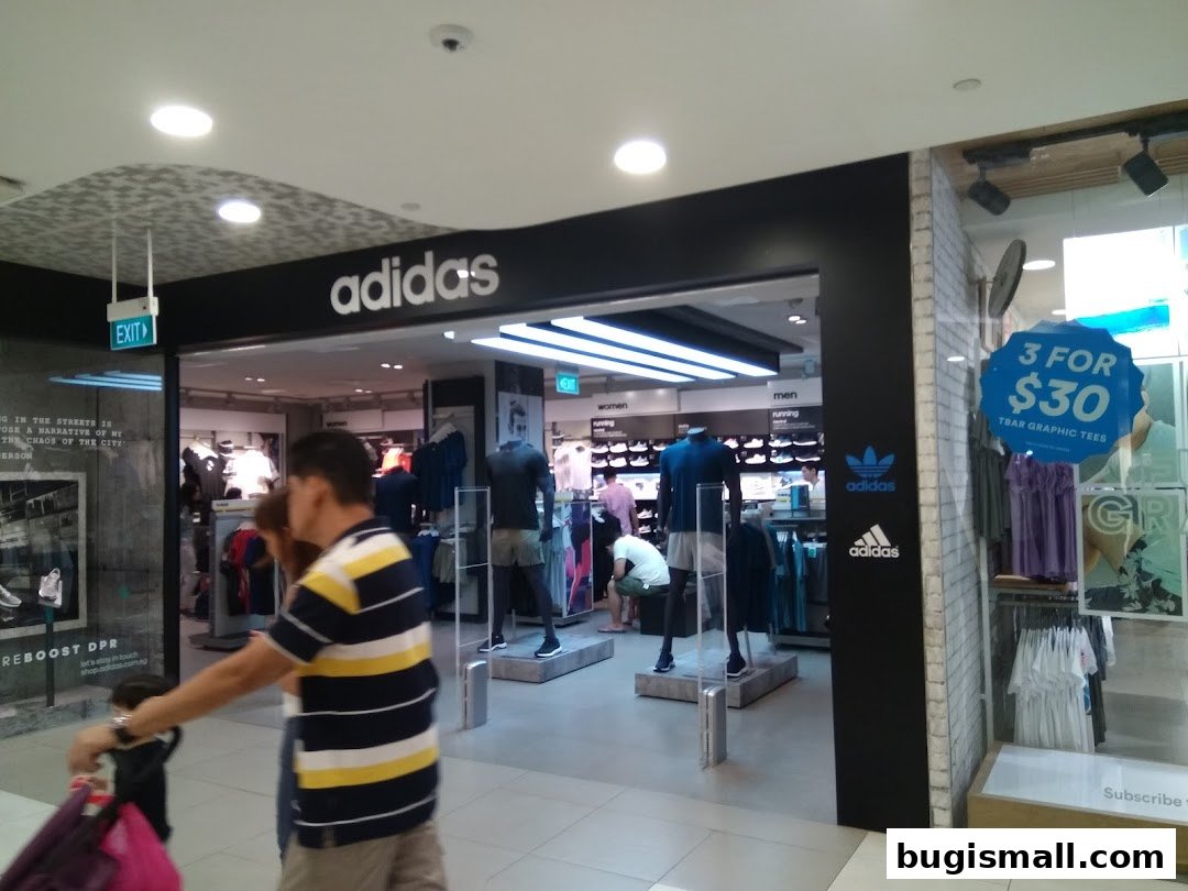 The entrance of an Adidas Originals store showcasing athletic apparel and a special offer.