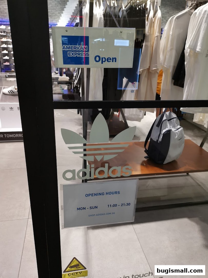 Adidas Originals store front with American Express payment accepted and opening hours displayed.