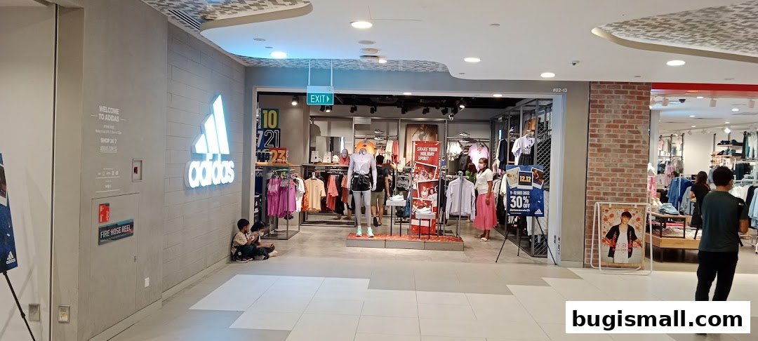 The entrance of an Adidas Originals store with clothing displays and mannequins.