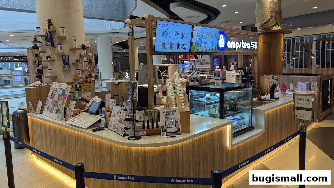 A modern tea shop counter with digital menus, merchandise, and a queue sign.