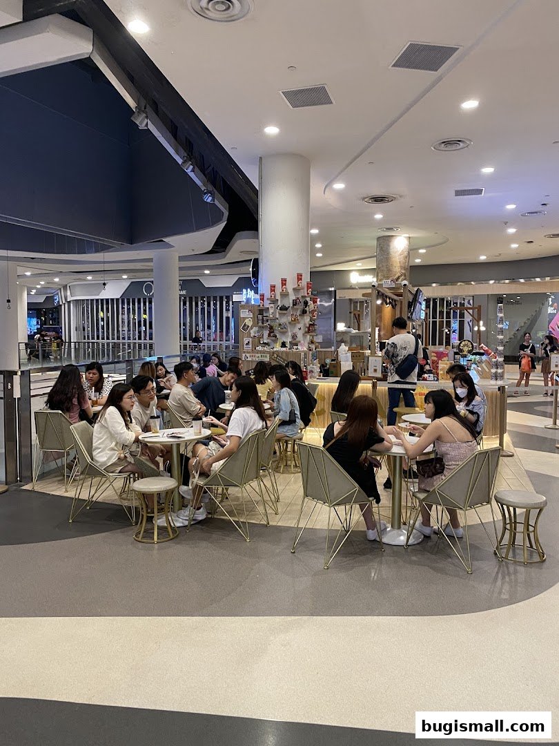 People enjoying drinks and snacks at tables inside a modern cafe.
