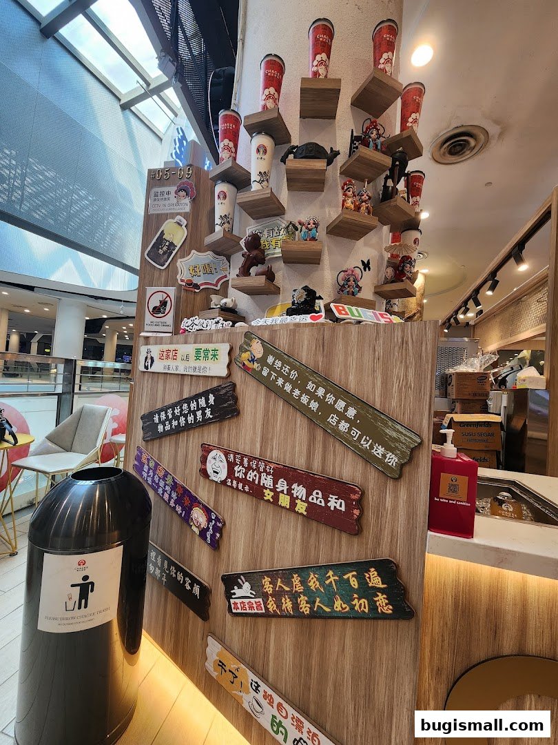 Shop interior with decorative cups, figurines, and humorous signs on a wooden wall.