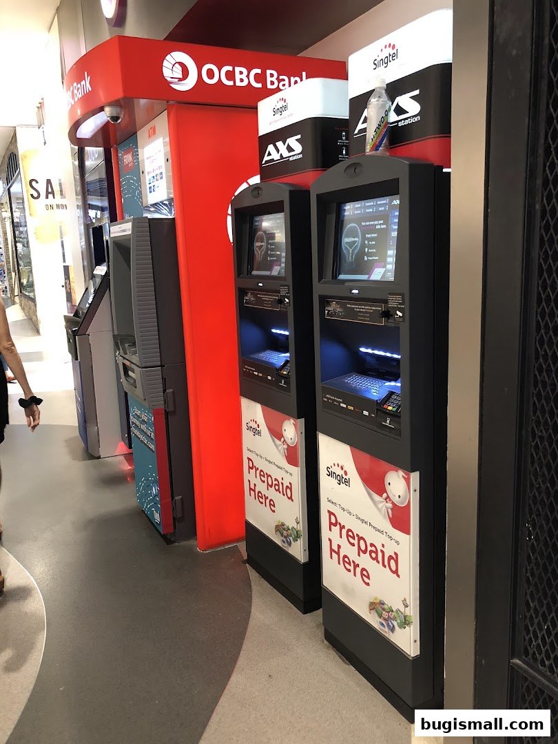 AXS Station kiosks and OCBC Bank ATM machines are lined up in a mall.