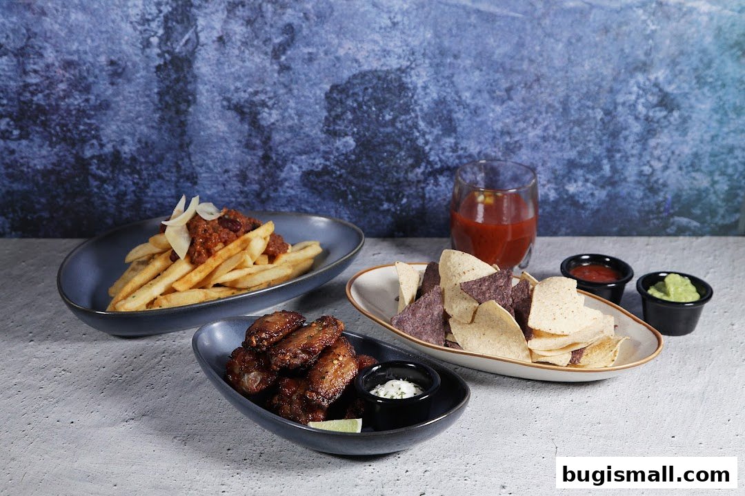 A spread of appetizers including chili cheese fries, chicken wings, and tortilla chips with dips.