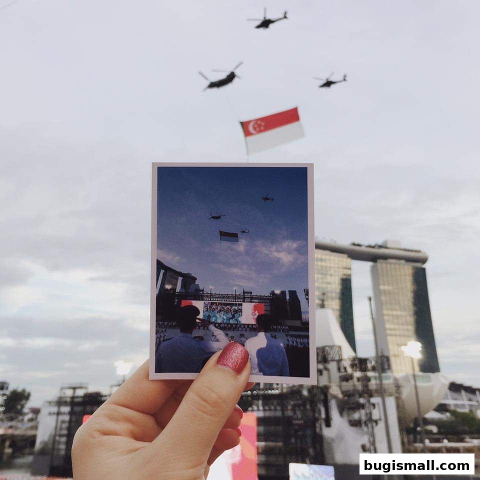 A hand holds a photo of a Singaporean flag and helicopters against the Marina Bay Sands.