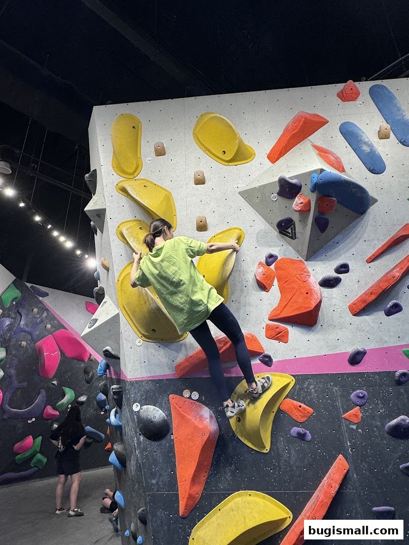 A person climbs a colorful bouldering wall with various holds.