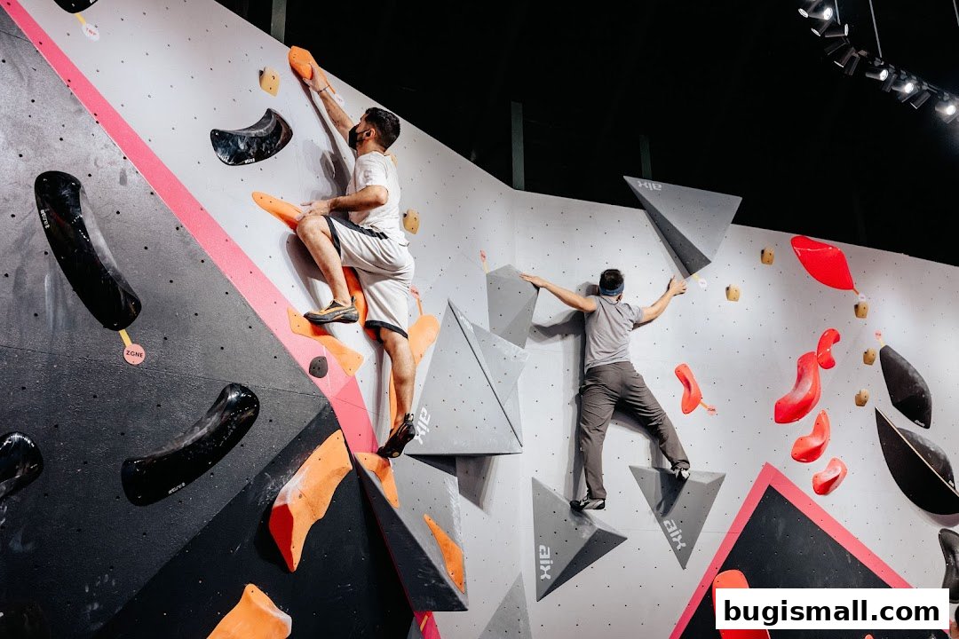 Two people bouldering on a colorful and challenging climbing wall with various holds.