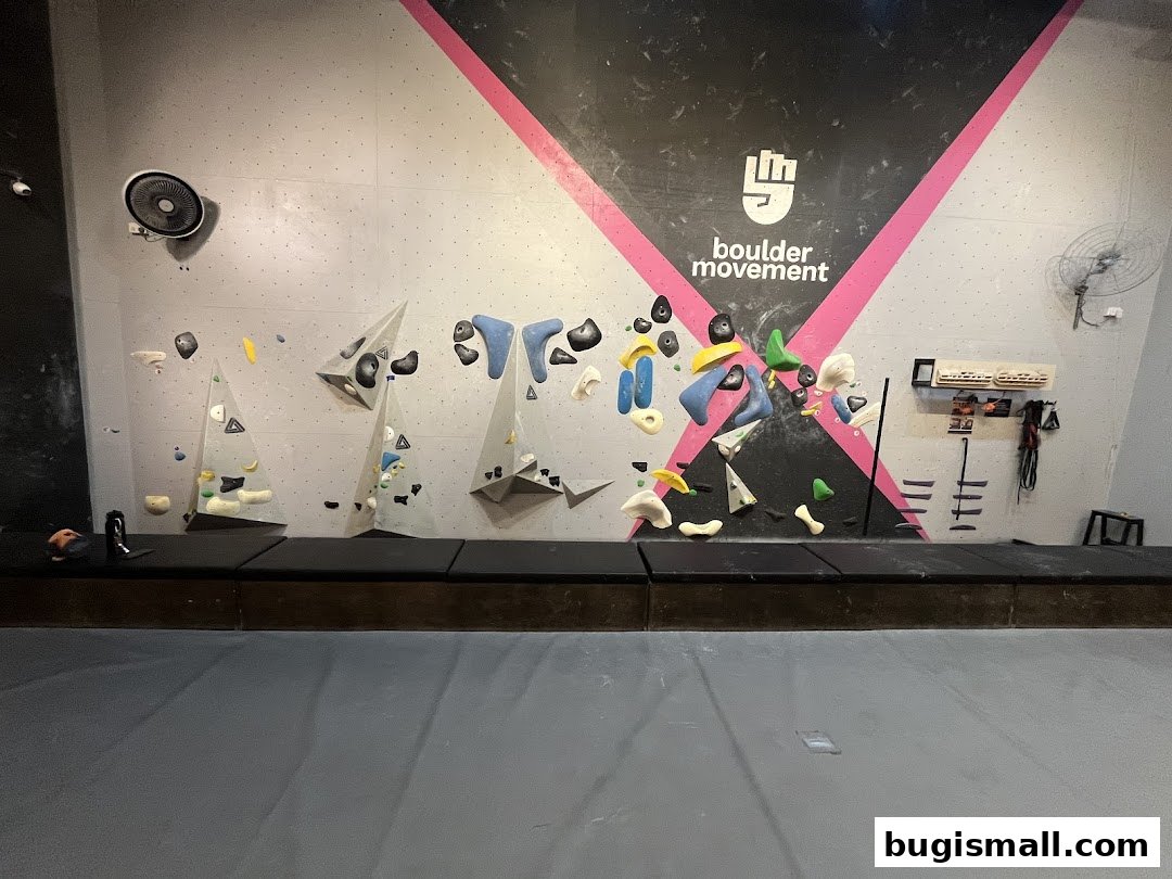 Interior view of a bouldering gym with climbing holds on a wall.