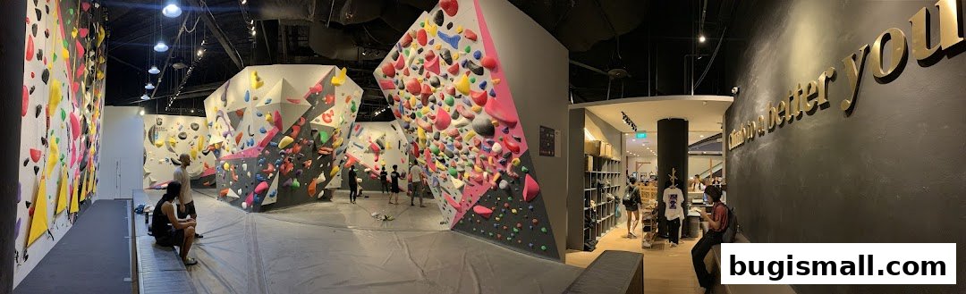 Interior of a bouldering gym with colorful climbing walls and people.