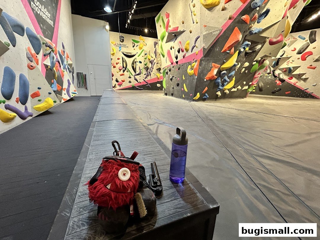 Interior view of a bouldering gym with climbing walls and chalk bag on a bench.