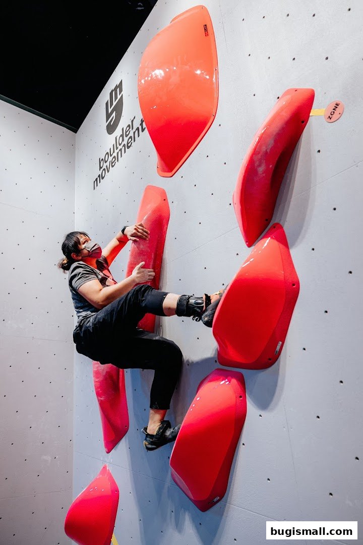 A person bouldering on a wall with bright red climbing holds.