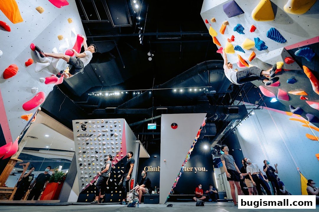 People bouldering and watching at an indoor climbing gym with colorful holds.