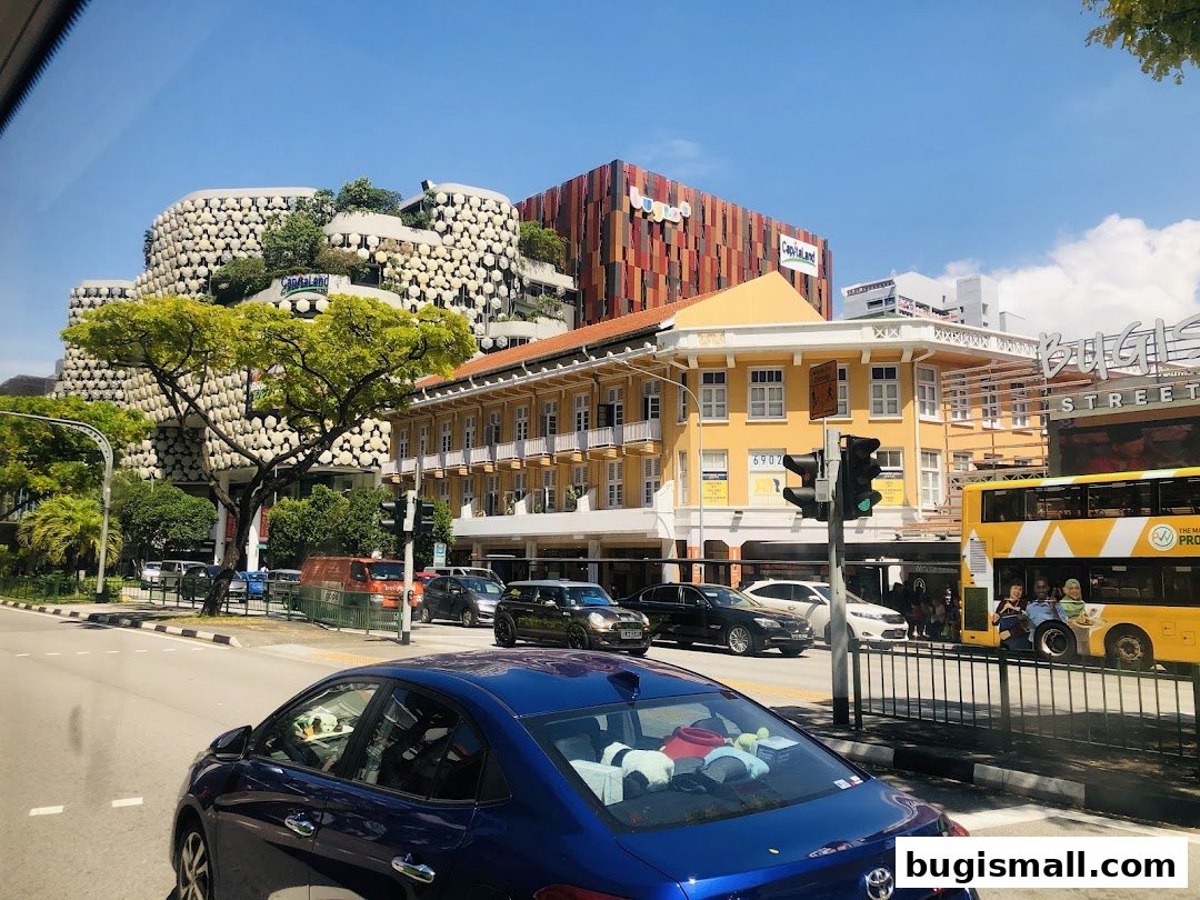 A street view of CapitaMalls Asia Limited - Bugis with unique architecture and a yellow double-decker bus.