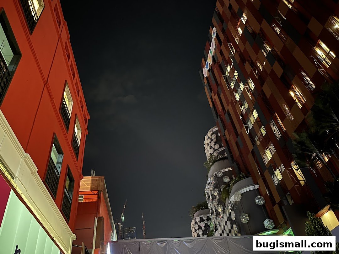 Night view of modern buildings with illuminated windows and unique architectural designs.