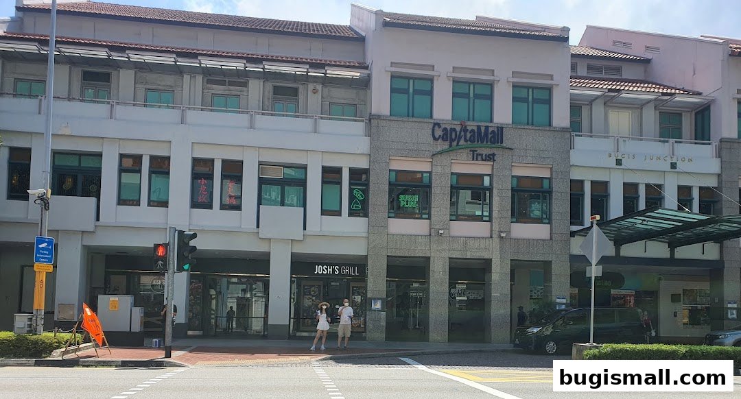 Exterior view of CapitaMall Trust Bugis Junction with various shops and people.