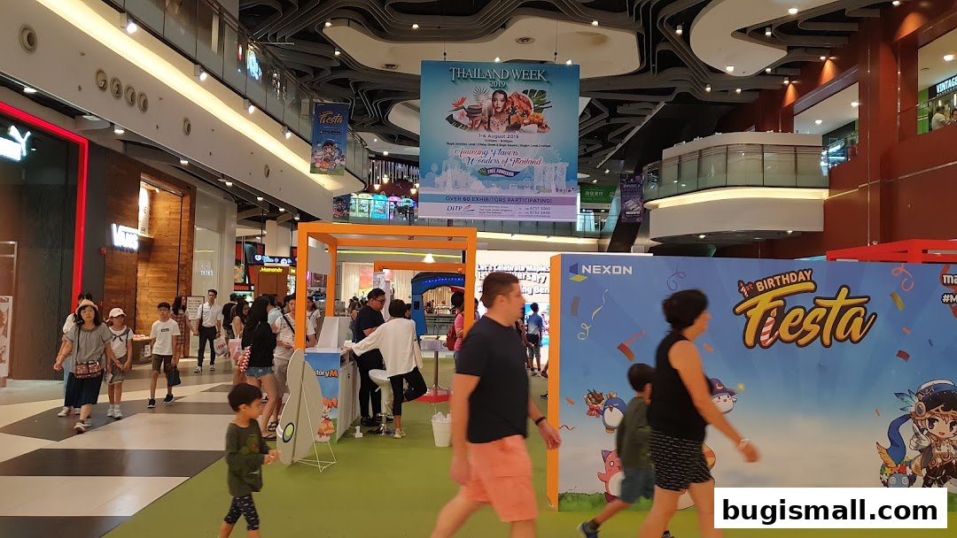 People walking through a mall with promotional banners for Thailand Week and a birthday fiesta.