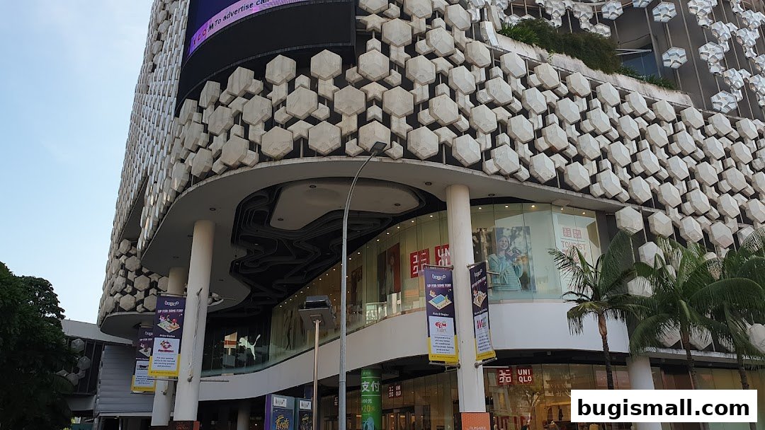Exterior view of a modern building with a unique geometric facade and shops on the ground floor.
