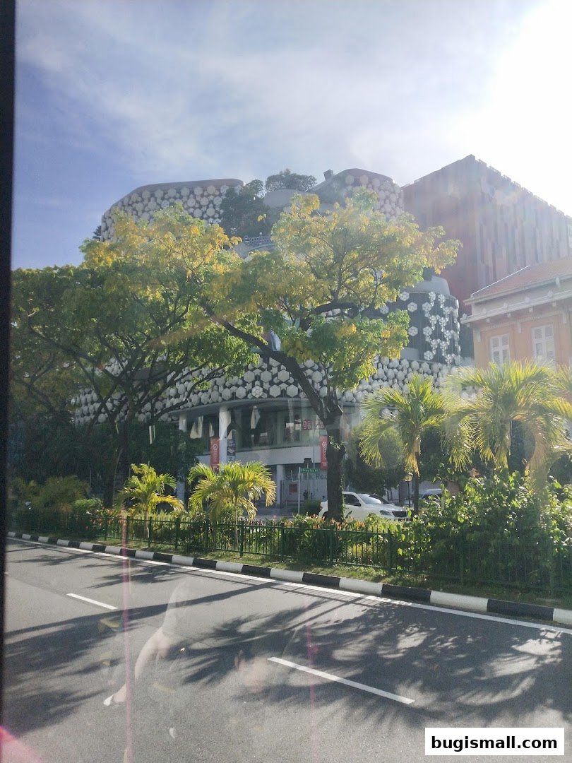 A modern building with unique facade, surrounded by trees and a street.
