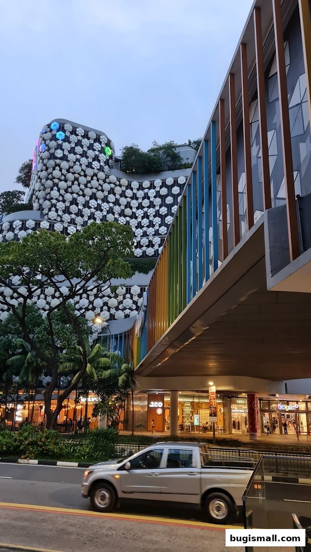 A modern building with a unique honeycomb facade and a colorful pedestrian bridge.