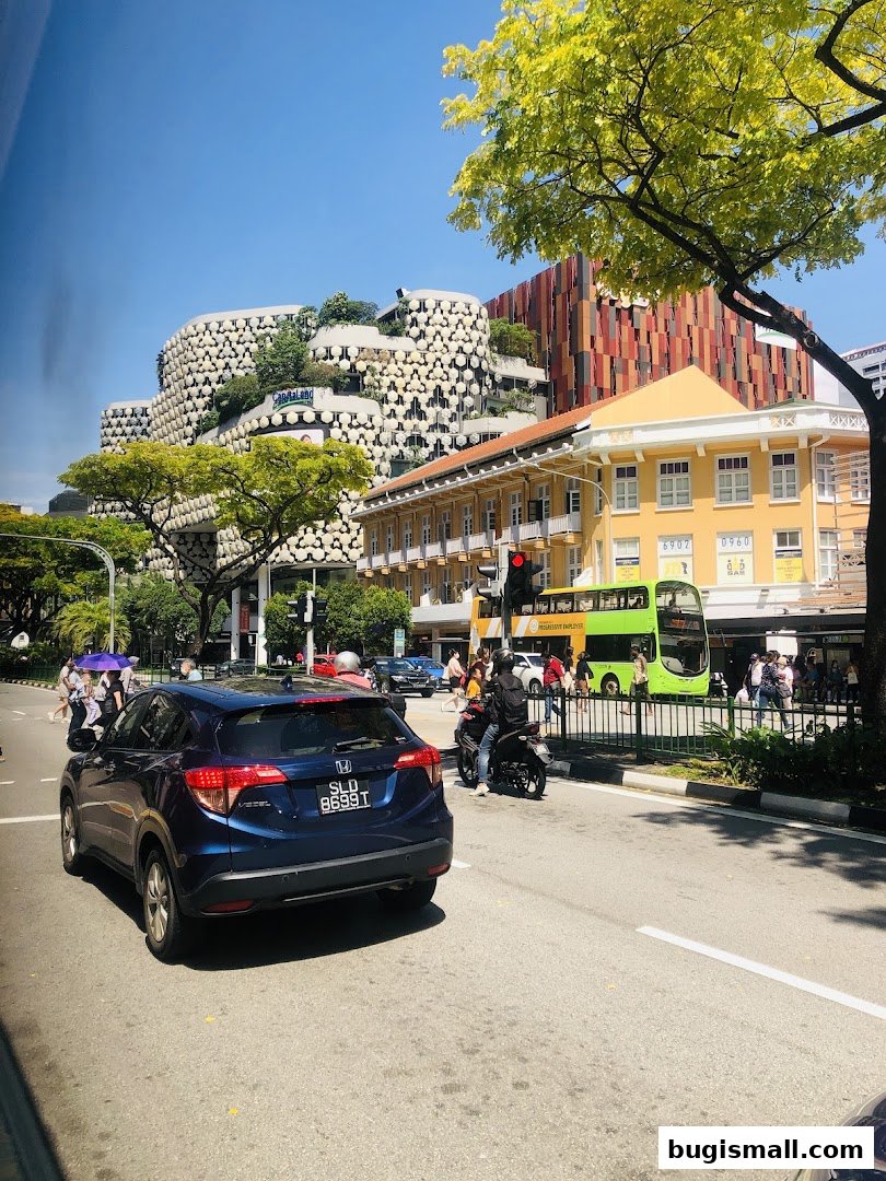 A street view of the CapitaMalls Asia Limited - Bugis building with unique architecture and surrounding city elements.