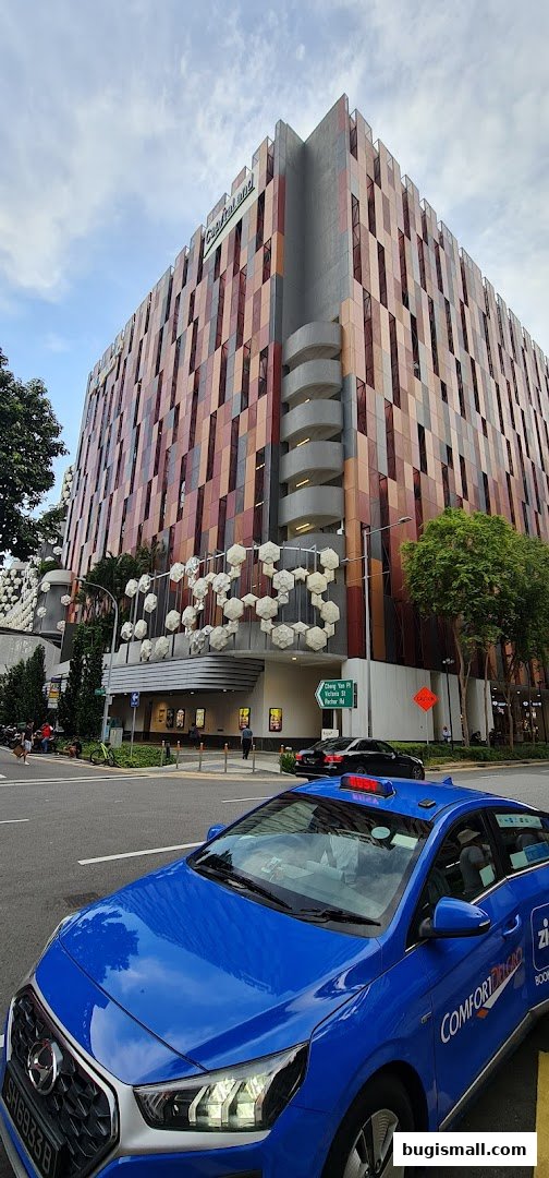 A modern building with a colorful facade and a blue taxi in the foreground.