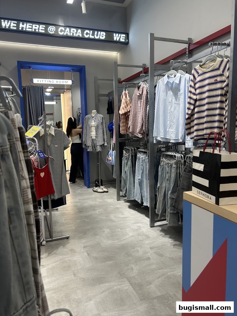 Interior view of Cara Club clothing store with apparel on racks and a fitting room.