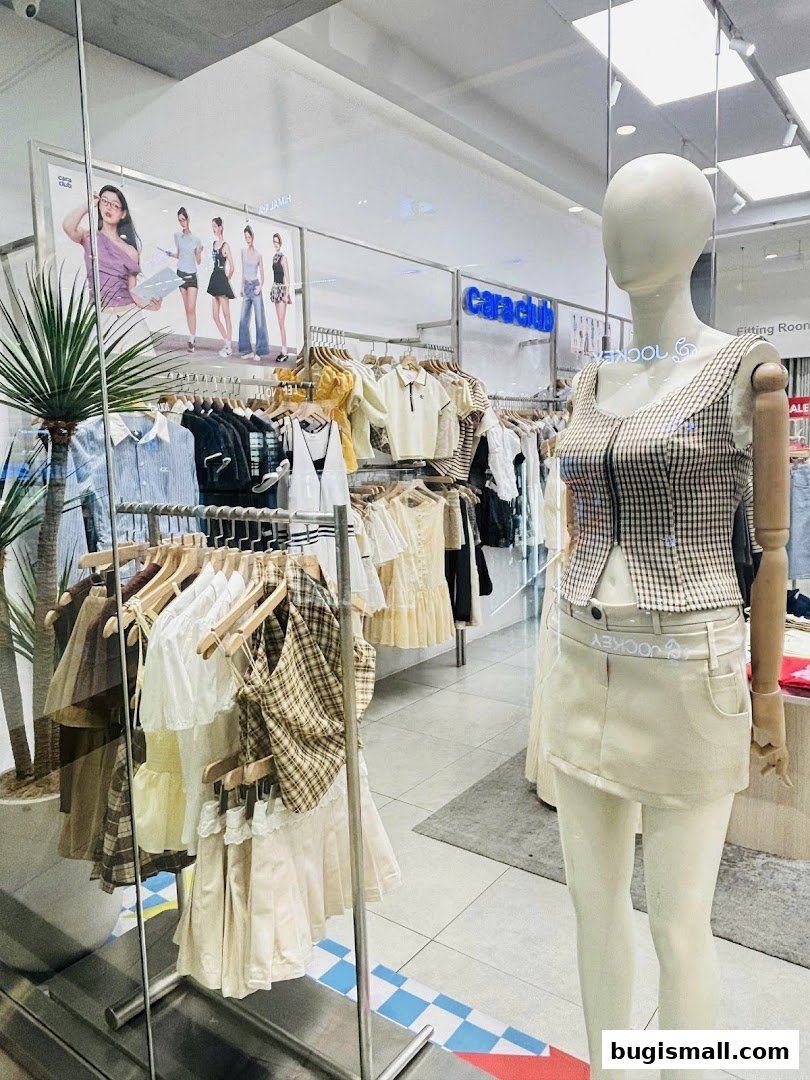 A fashion store window display featuring mannequins and racks of stylish clothing.