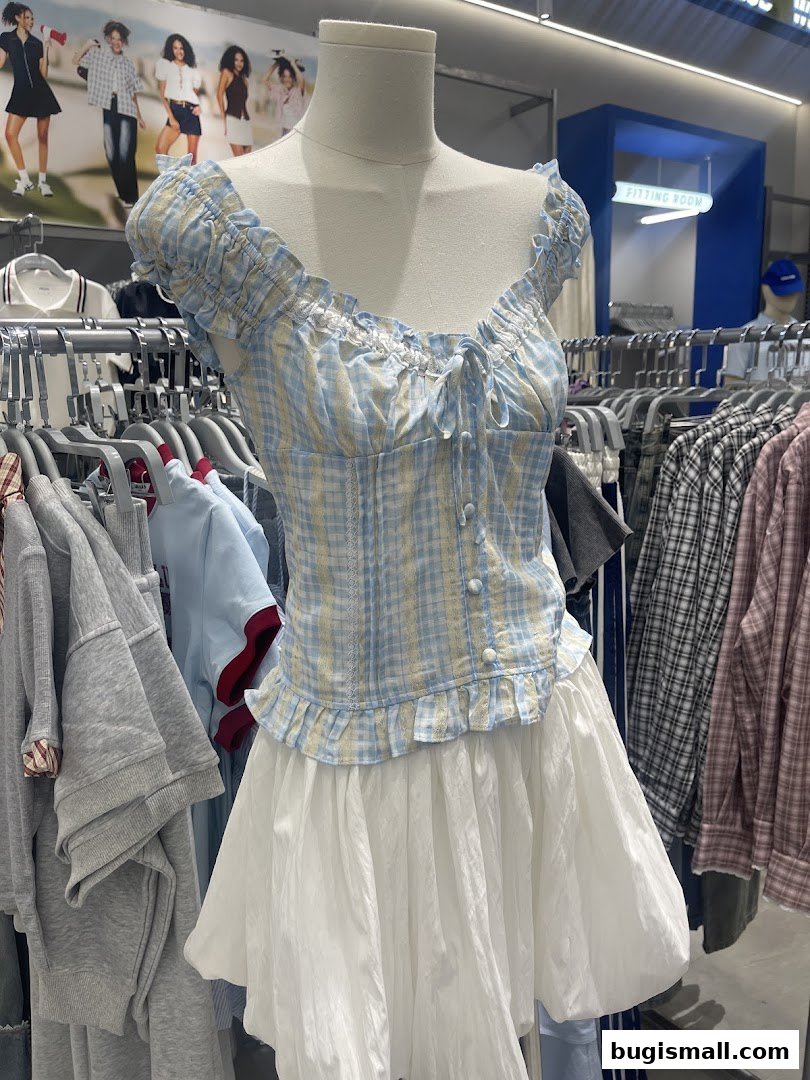 A mannequin displays a blue and yellow checkered top with a white skirt in a clothing store.