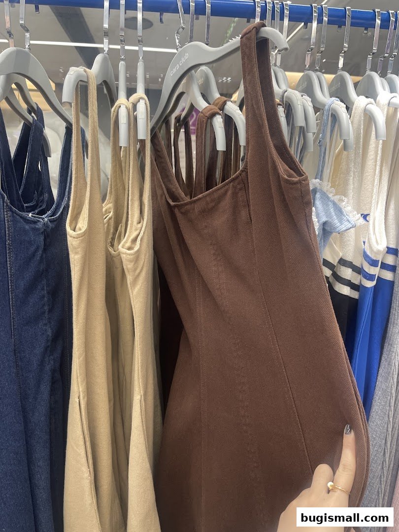 A selection of women's dresses and tops hanging on hangers in a store.