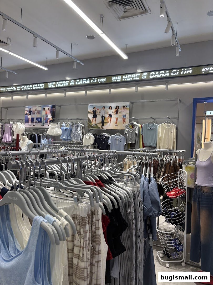 Interior view of a clothing store with racks of apparel and promotional images.