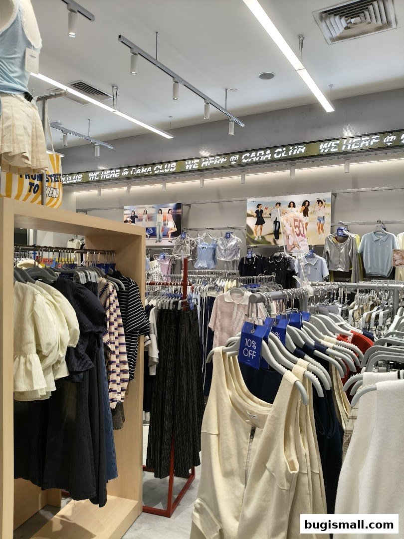 Interior view of a clothing store with racks of apparel and a neon sign.