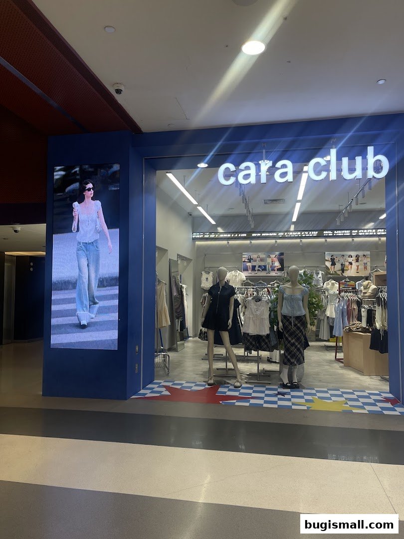 The Cara Club shop front displays trendy clothing on mannequins and racks, with a digital screen showing a fashion model.