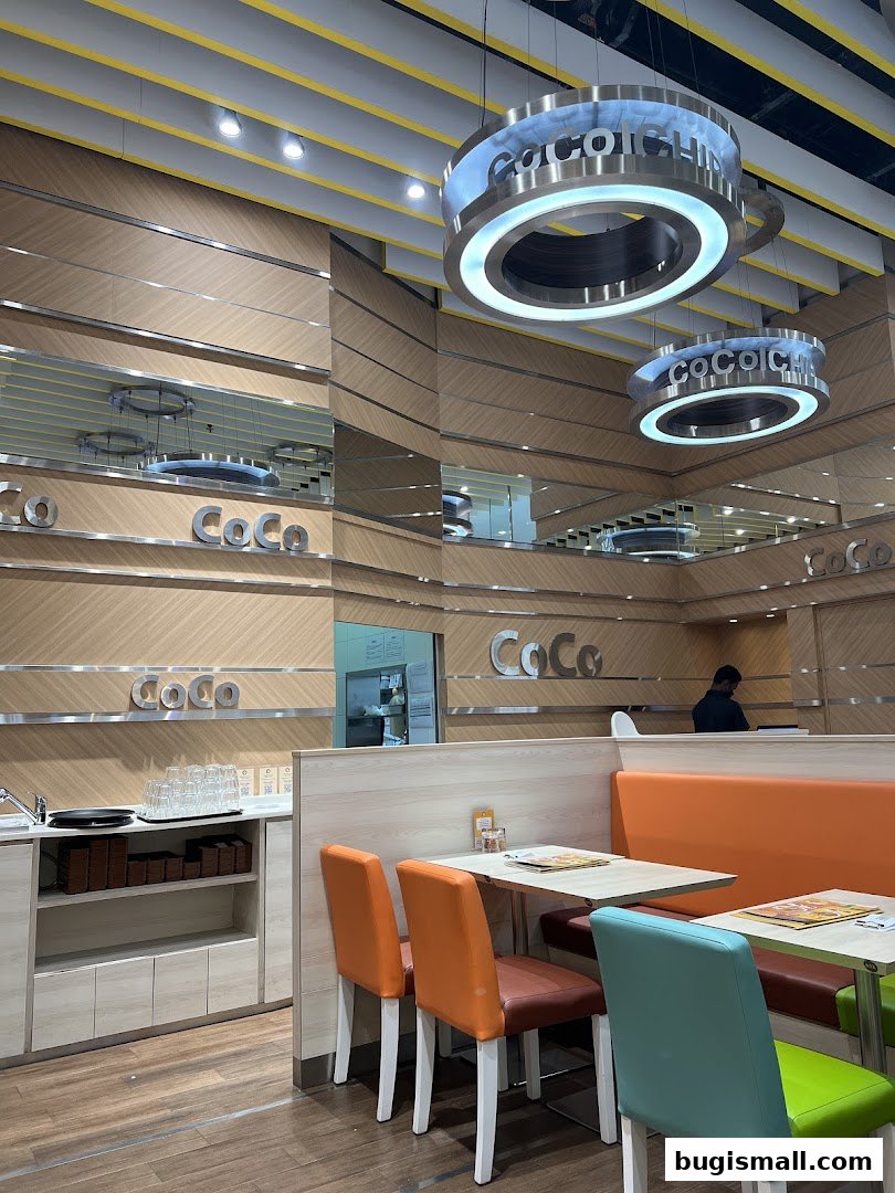 Interior of CoCo Ichibanya restaurant with dining tables, chairs, and distinctive pendant lights.