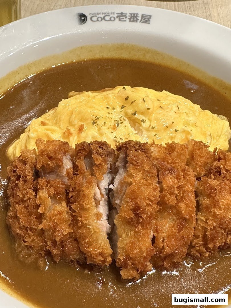 A close-up of a delicious Japanese curry dish with crispy katsu and fluffy omelet.