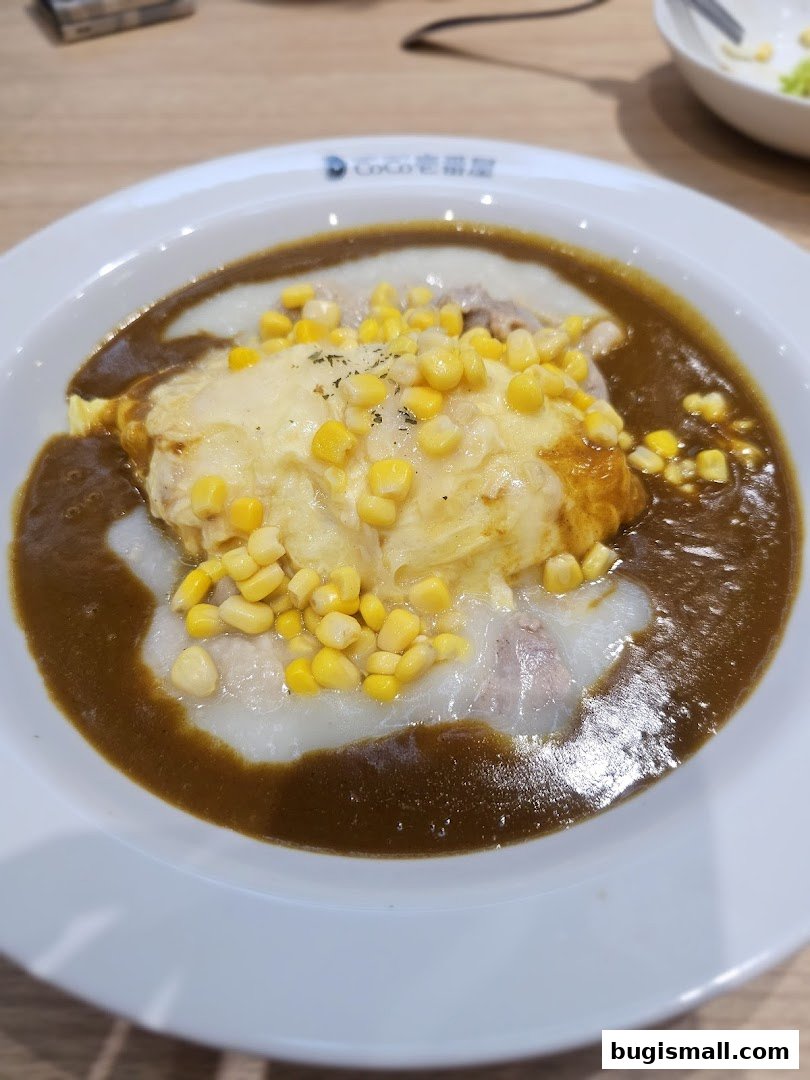 A close-up of a delicious Japanese curry dish with omelet, corn, and meat.