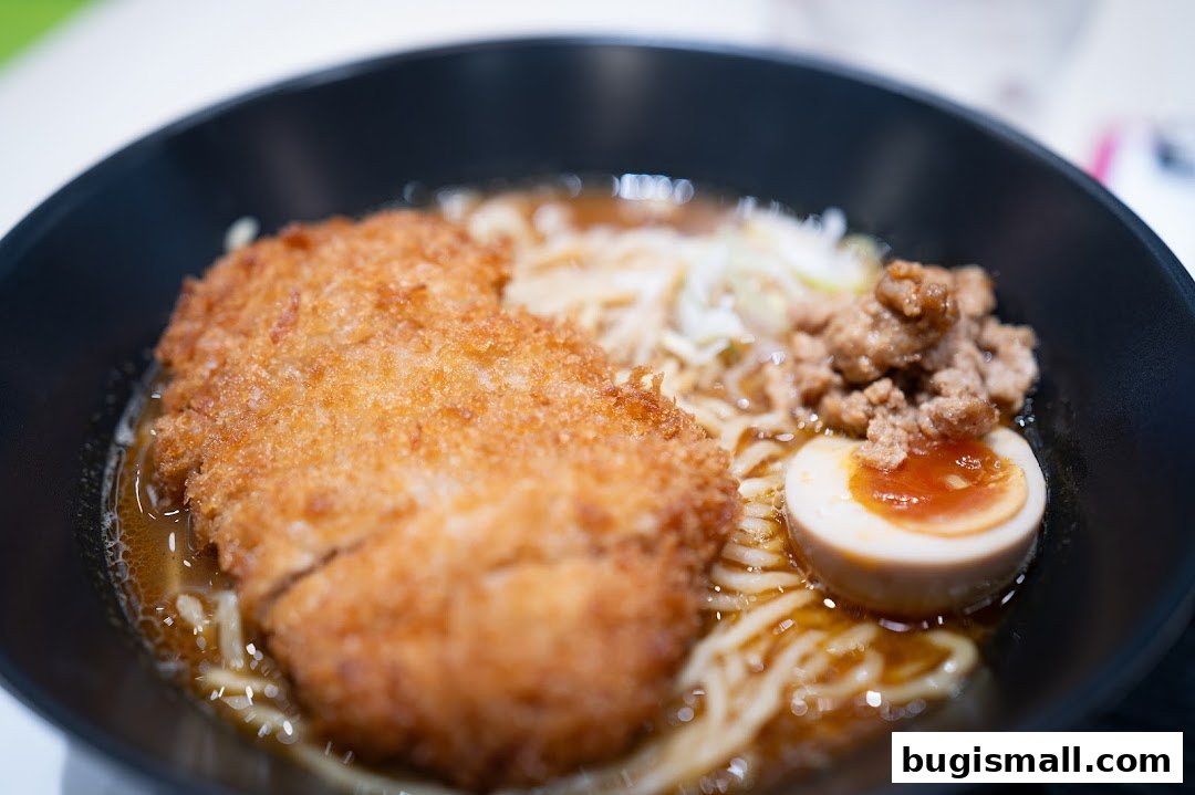 A close-up shot of a delicious bowl of ramen with crispy fried chicken and a soft-boiled egg.