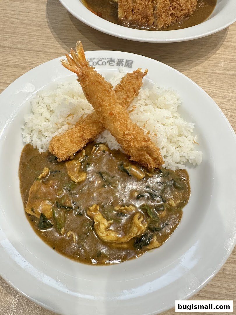 A plate of Japanese curry with rice, topped with crispy fried shrimp.