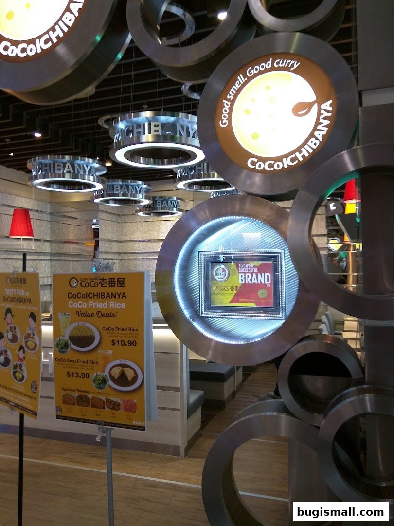 Interior view of CoCo Ichibanya restaurant with decorative lighting and promotional posters.