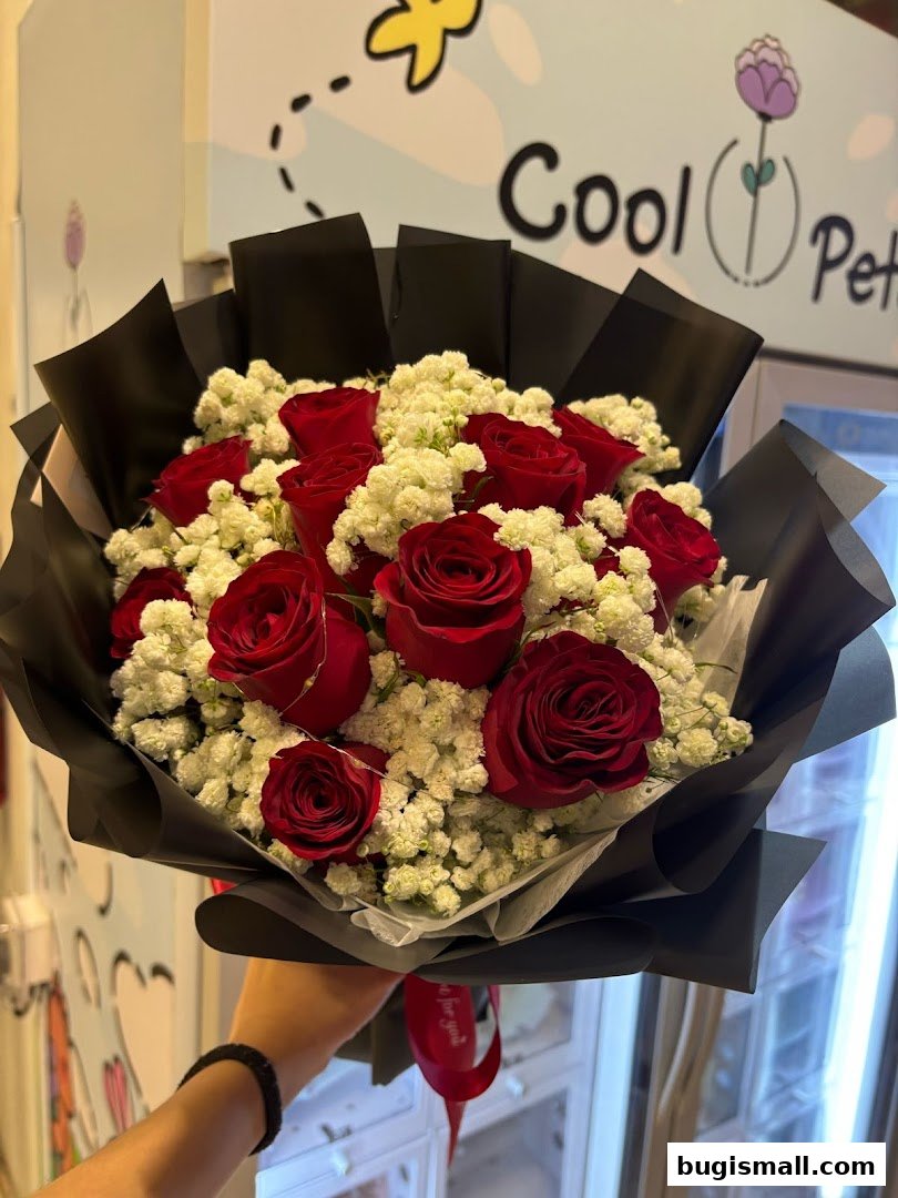 A hand holds a bouquet of red roses and baby's breath, with the shop name 'Cool Petals' visible.