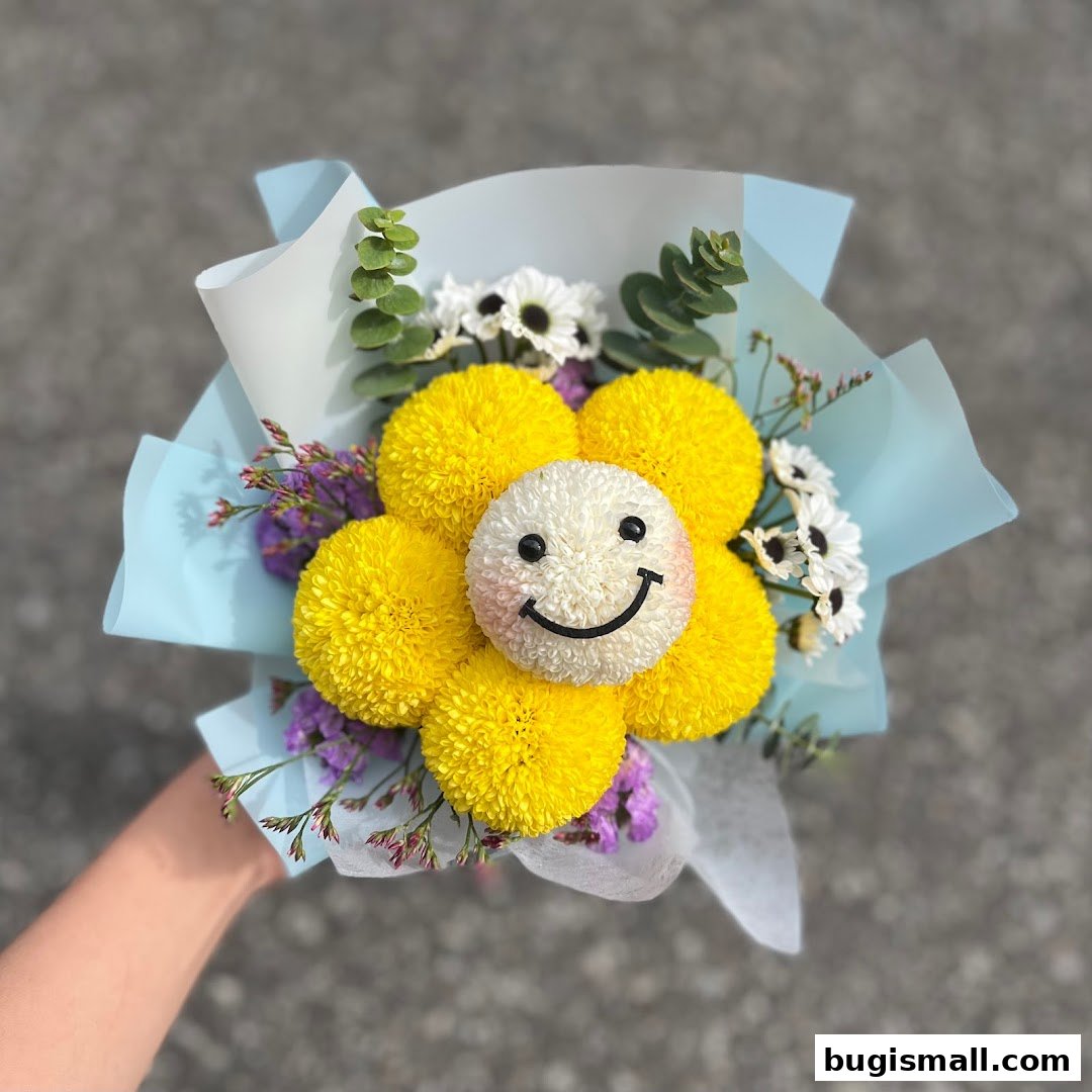 A hand holds a cheerful bouquet of yellow chrysanthemums with a smiley face in the center.