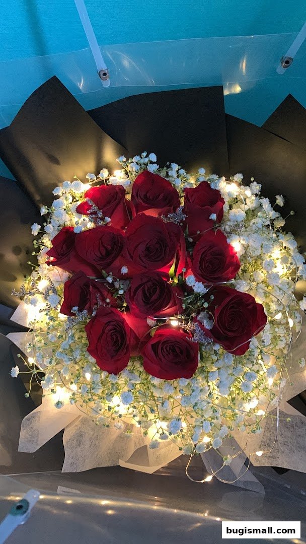 A bouquet of red roses and baby's breath with fairy lights.